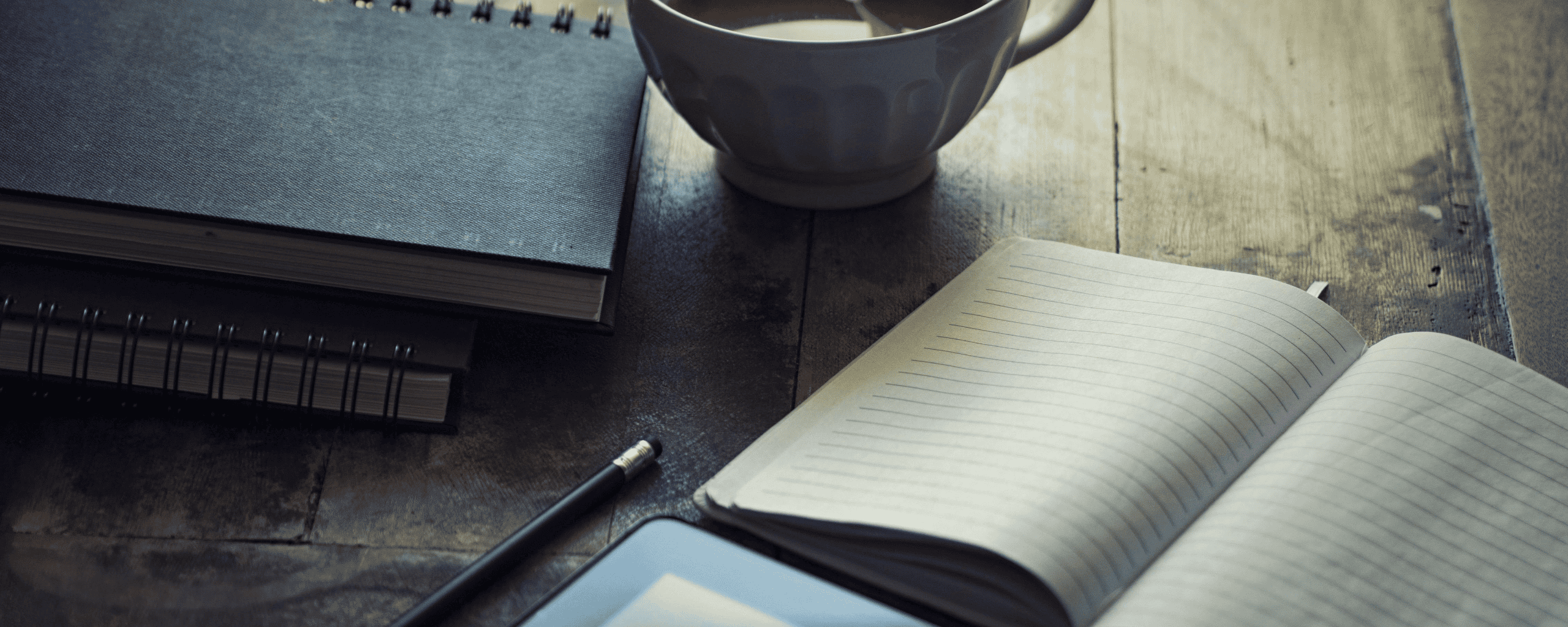 Notepads and coffee laid out on a desk